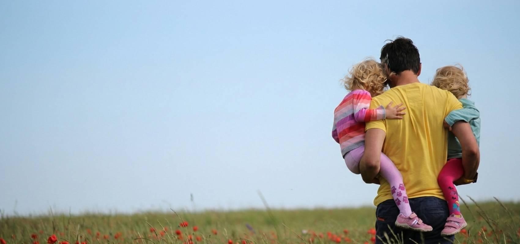 Un parent portant deux enfants dans un champ